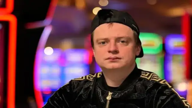 Portrait de Mellstroy475, streamer de casino en ligne, devant des machines à sous dans un décor de casino