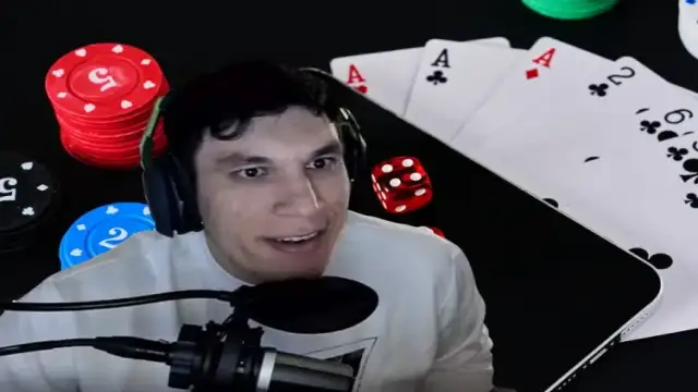 Trainwreckstv parlant au micro lors d’un stream de casino, avec jetons, cartes et dés visibles à l’écran