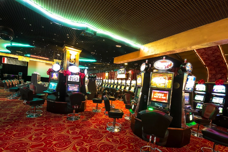 Sala delle slot machine al Casino Barrière di Tolosa con poltrone nere, luci al neon e moquette rossa decorata