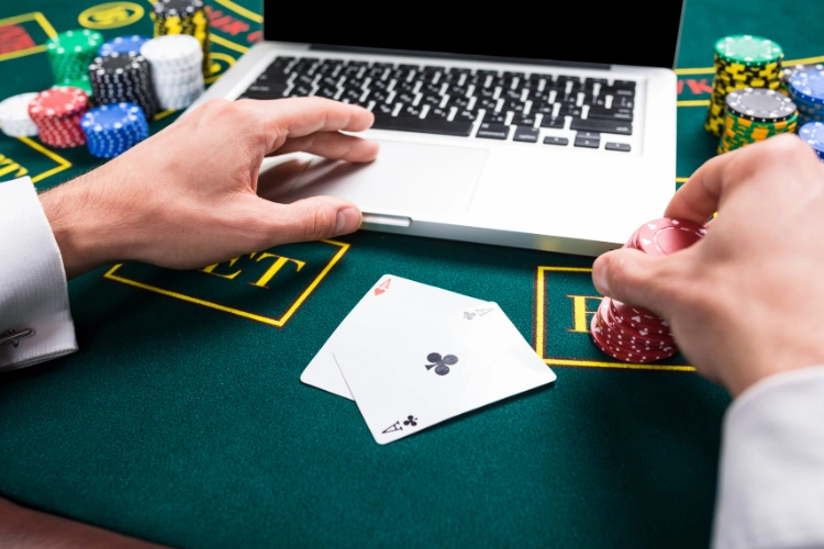 An online player betting chips at blackjack on a casino table with a laptop