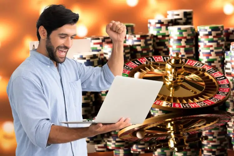 Happy player in front of his computer with a roulette wheel and chips in the background – illustration of strategies to maximize winnings